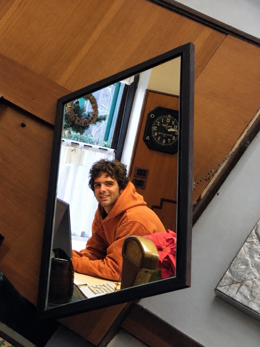 Tommaso Gibertini alla scrivania del negozio, riflesso in uno specchio
